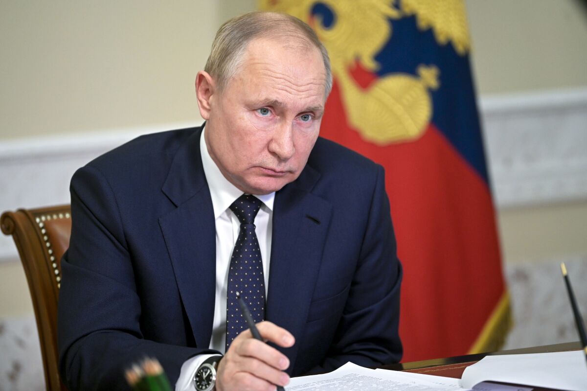 Russian President Vladimir Putin sits at a desk