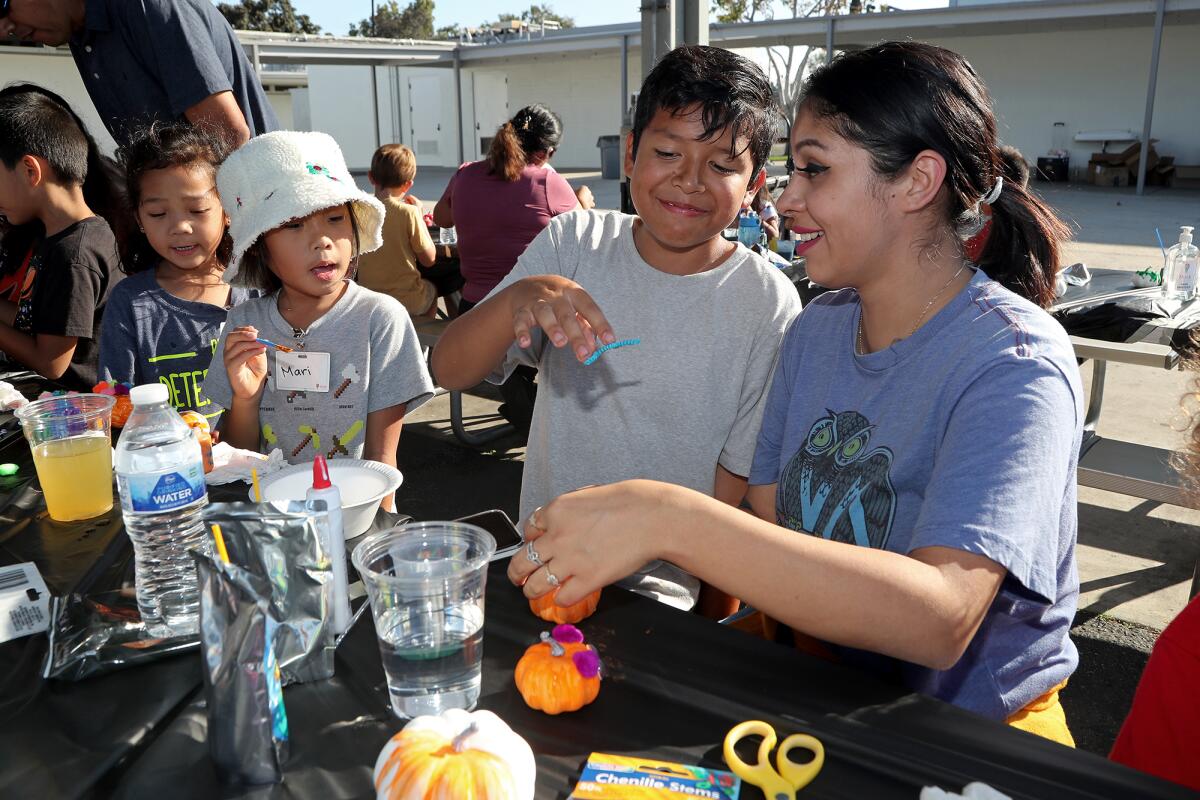 Greg Montiel, 11, center, and his mother, Elena, right, participate in a pumpkin decorating activity.