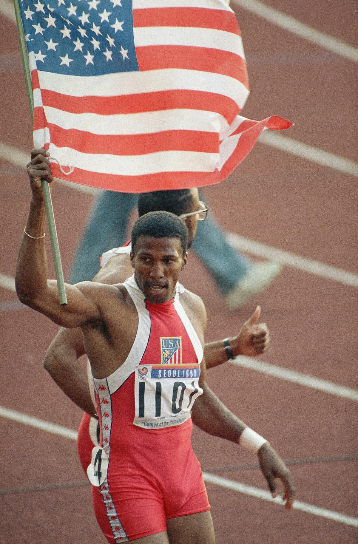 Roger Kingdom carries an American flag after winning the gold medal in the 110-meter hurdles in the 1988 Olympics.