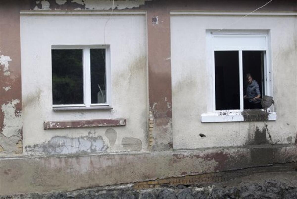 A resident cleans her damaged house after a flash floods hit the town of Bogatynia, Poland, Sunday, Aug. 8, 2010. The flooding has struck an area near the borders of Poland, Germany and the Czech Republic. (AP Photo/Petr David Josek)