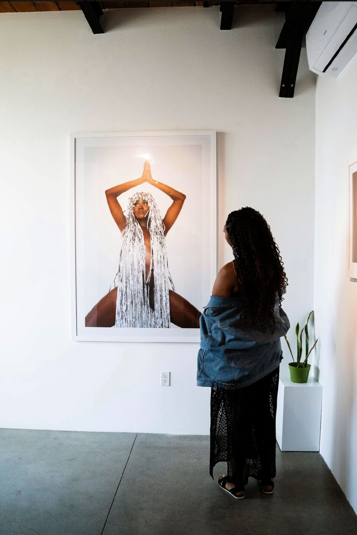 A woman stands facing a hanging photograph.