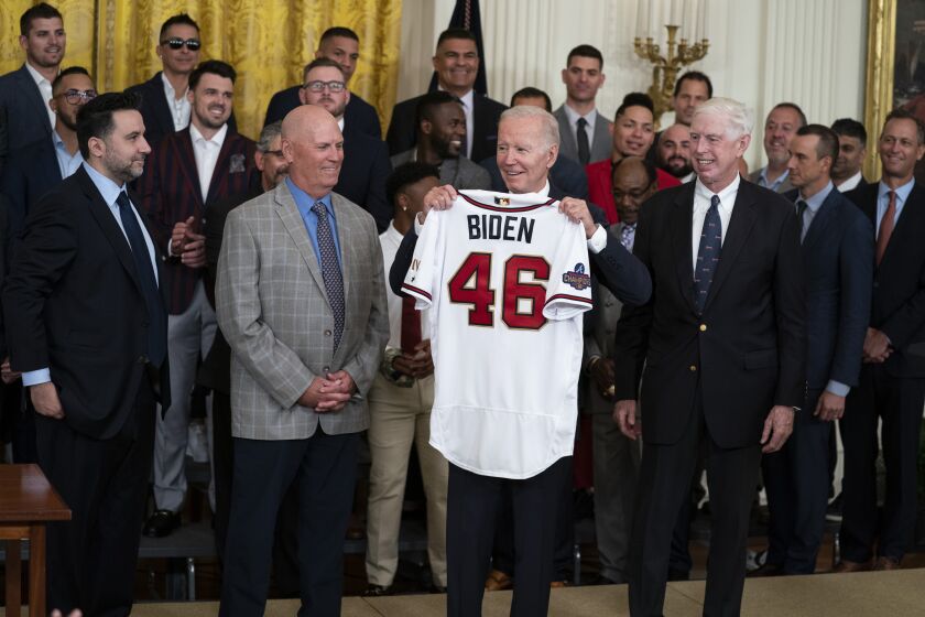 El presidente Joe Biden alza una casaca durante un acto en la Casa Blanca para homenajear a los Bravos de Atlanta, campeones de la Serie Mundial, el lunes 26 de septiembre de 2022. (AP Foto/Evan Vucci)