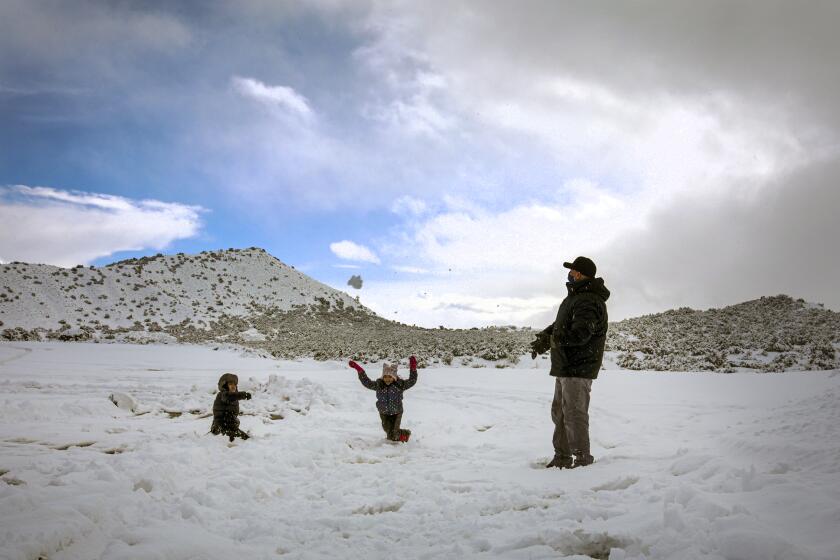 Phelan, CA - January 29: Adrian Rios, right, and his children Ian Rios, left, and Susan Rios play in freshly fallen snow along Highway 138 on Friday, Jan. 29, 2021 in Phelan, CA.(Irfan Khan / Los Angeles Times)