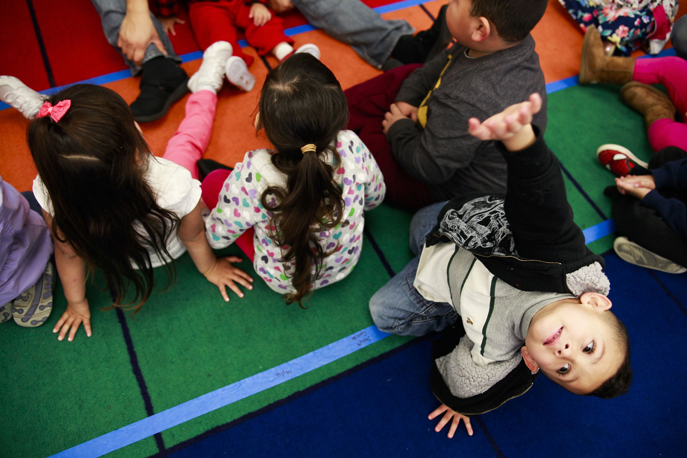 Un niño levanta el brazo durante una lección mientras asiste a la guardería con otros niños 