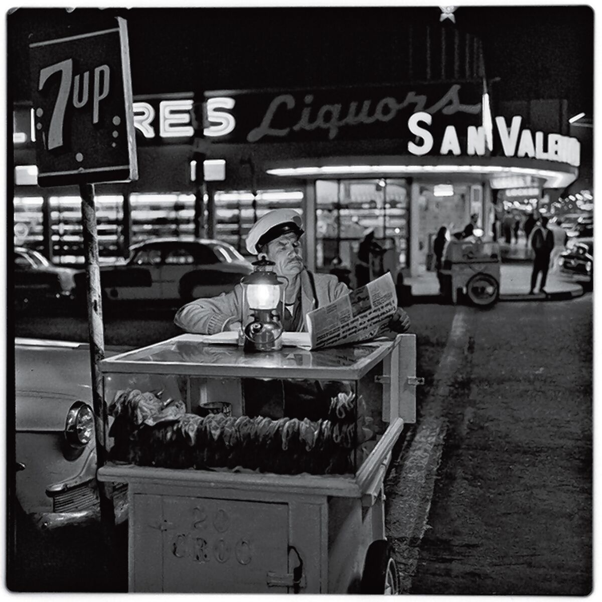 A taco vendor catches up on the day’s news in this 1964 photograph by Harry Crosby from the collection of Paul Ganster.