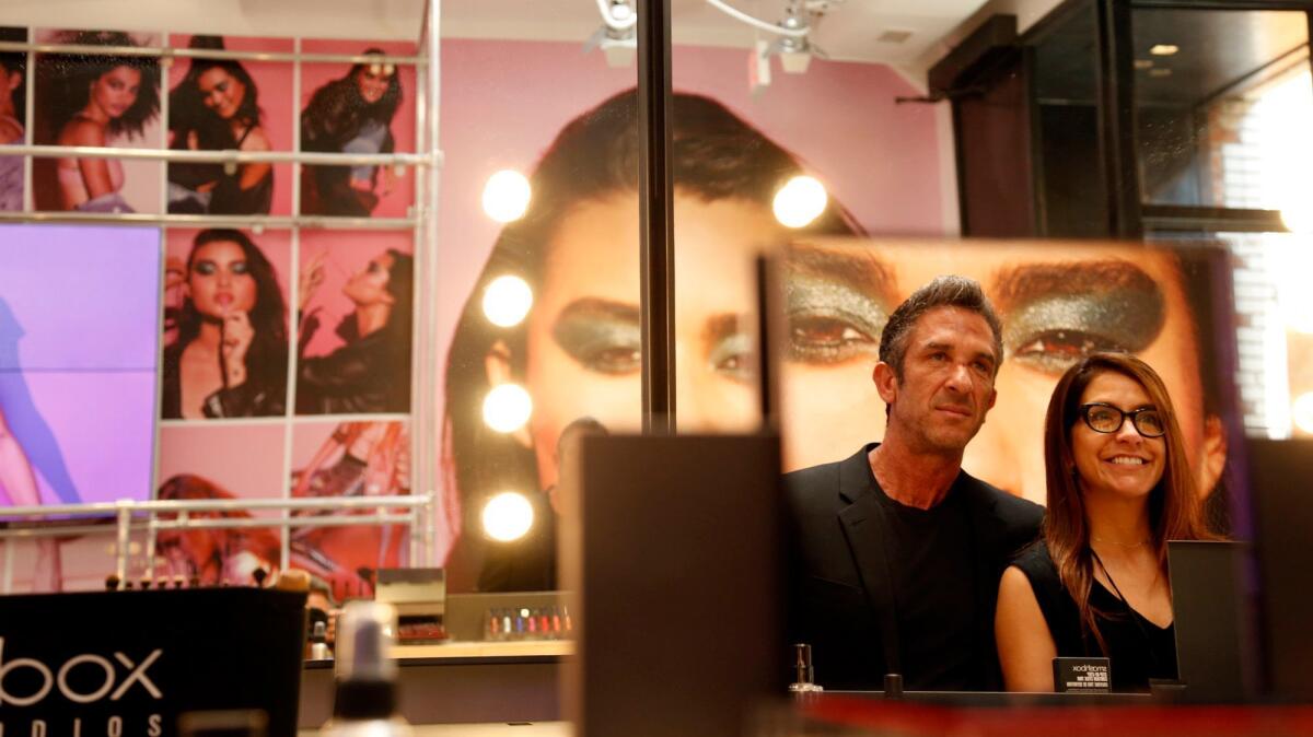 Reflected in a makeup mirror are photographer Davis Factor, Smashbox co-founder and senior vice president of global creative, and Beth DiNardo, global brand president of Smashbox, who stand inside their new Smashbox store on Abbott Kinney Boulevard in Venice. (Genaro Molina / Los Angeles Times)