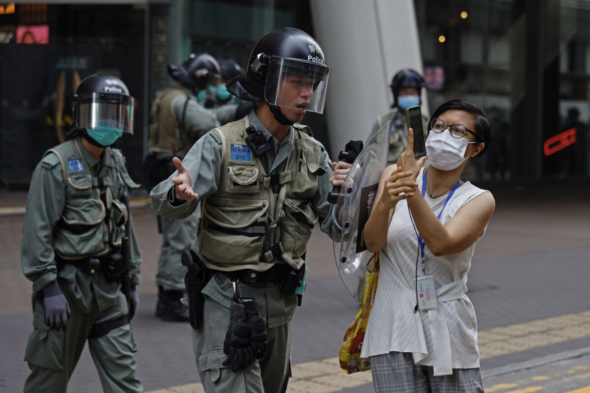 A riot officer pushes a woman photographing detained protesters in Hong Kong's Mong Kok district on May 27, 2020.
