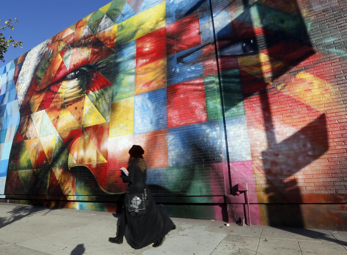 A passerby walks in front of a painting featuring the face of Nelson Mandela in Hollywood on Thursday.