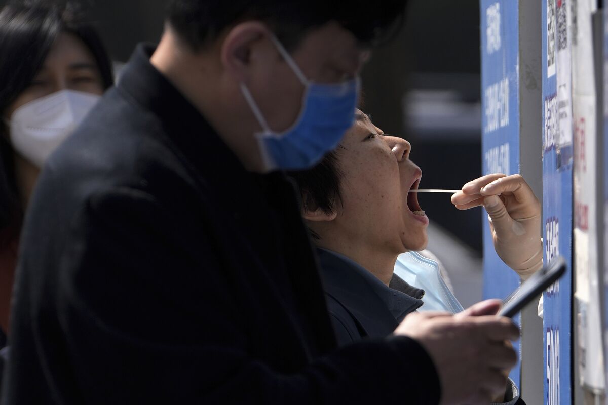 Residents line up to get their throat swab at a coronavirus testing site in Beijing. 