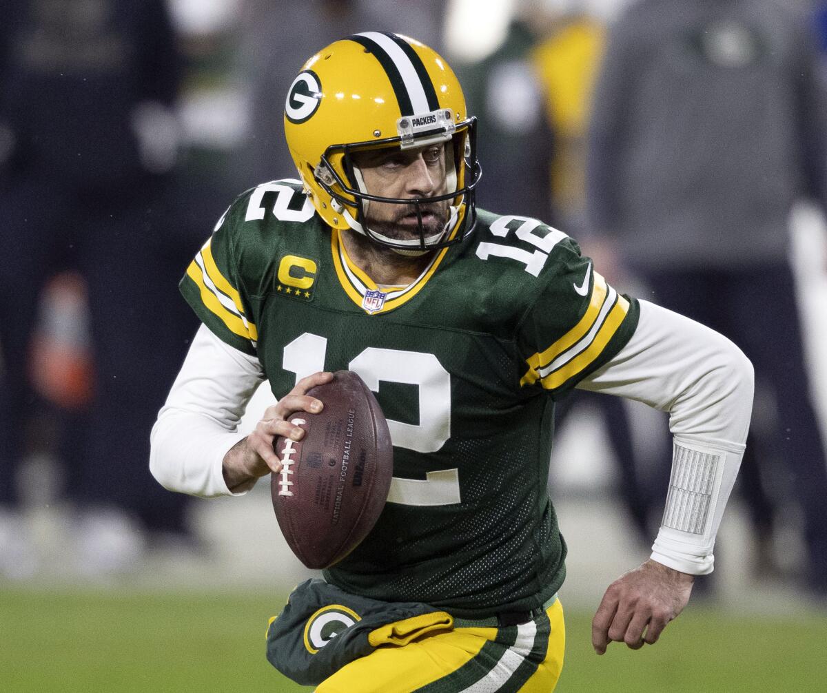FILE - In this Jan. 16, 2021, file photo, Green Bay Packers quarterback Aaron Rodgers (12) runs during an NFL divisional playoff football game against the Los Angeles Rams in Green Bay, Wis. Packers general manager Brian Gutekunst says the team remains committed to Rodgers “for the foreseeable future” one year after trading up in the first round to draft the three-time MVP’s potential successor. (AP Photo/Jeffrey Phelps, File)