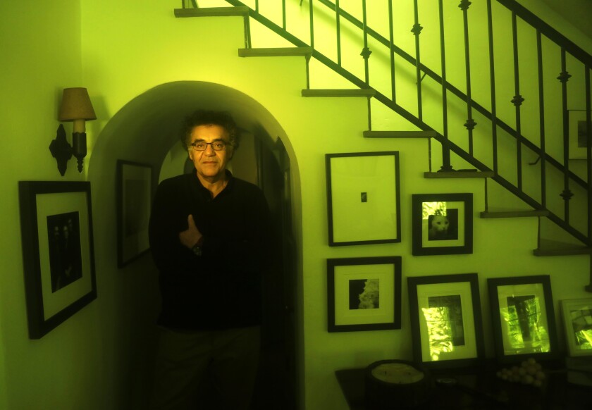 A man stands next to a staircase inside a house.