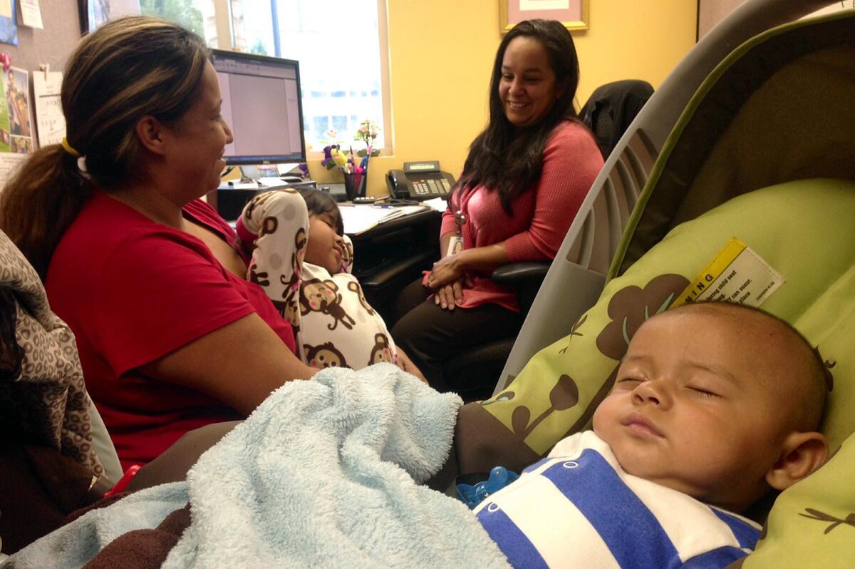 Annette Diaz holds her daughter, Kayla Valenzuela, 2, while her son Johnie Valenzuela, 5 months, sleeps, in the Health Benefits Resource Center at St. Francis Medical Center in Lynwood, one of many locations providing information about the start of Obamacare.