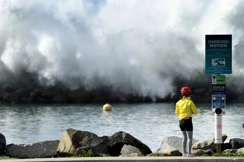 Redondo Beach, California January 11, 2023-A woman watches a wave crash over the Redondo Beach breakwater Wednesday as storms in the Pacific created big swells. (Wally Skalij/Los Angeles Times)