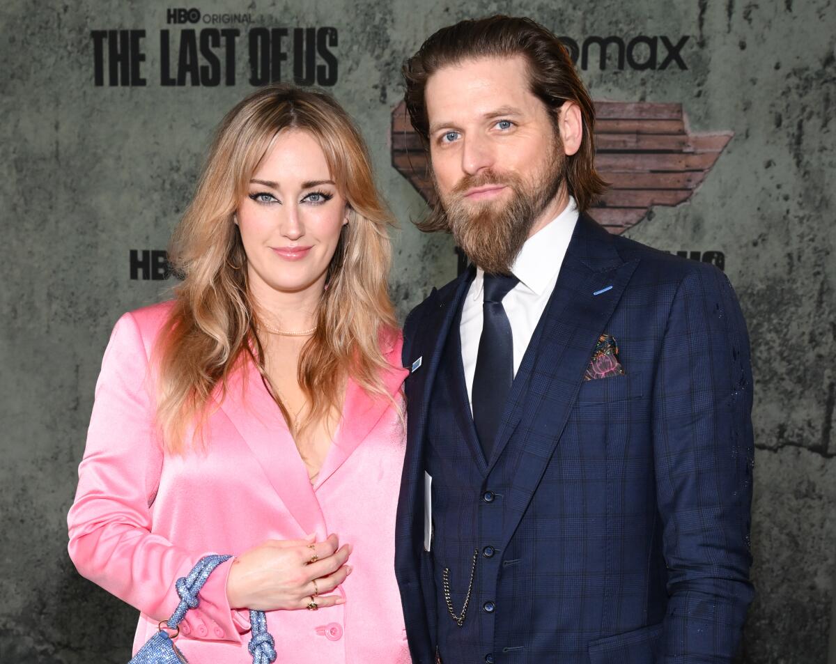 Ashley Johnson wears a pink suit and Brian W. Foster wears a plaid navy suit. 