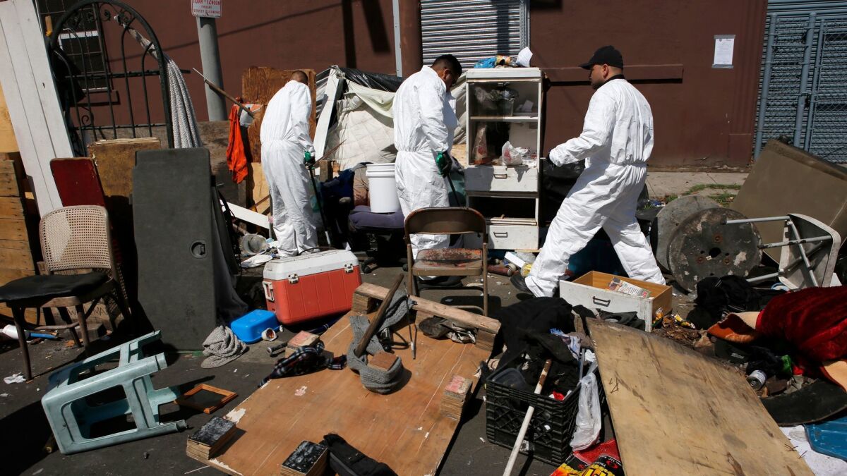 Sanitation workers clean and dispose of chemicals, human feces and sharp objects at a homeless encampment in Los Angeles last month.