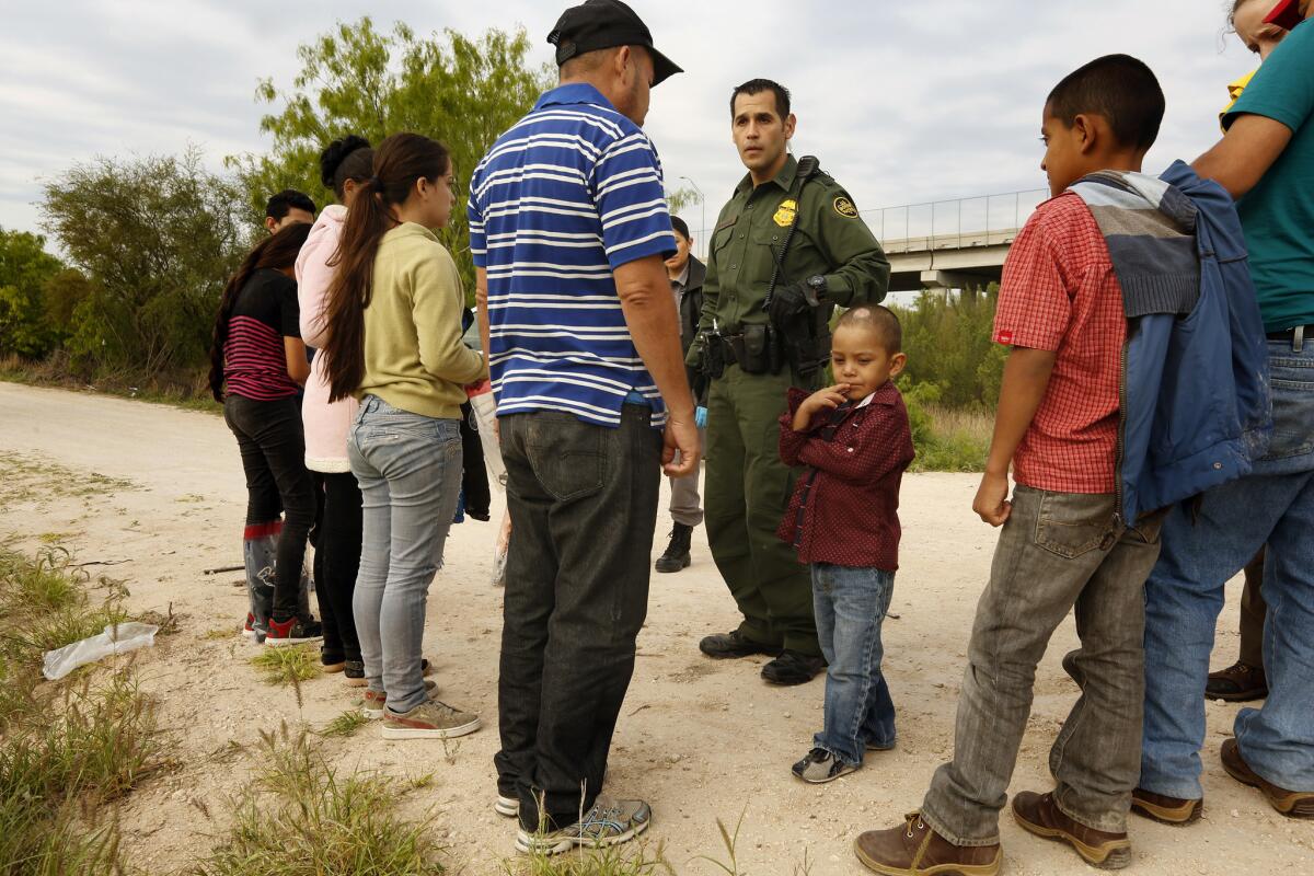 Ely Fernandez is questioned by Border Patrol Agent Robert Rodriguez after being detained with son Bryan, 5, center.