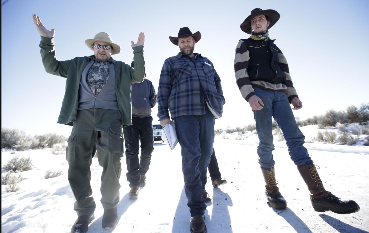 Men in cowboy hats and boots walk along a snowy road.