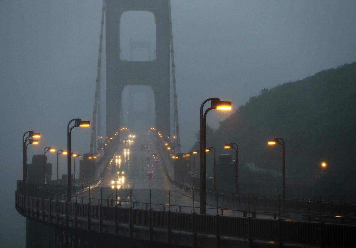 Traffic moves slowly across the Golden Gate Bridge in high winds and rain on Thursday. The Bay Area was hit by flooding and power outages.