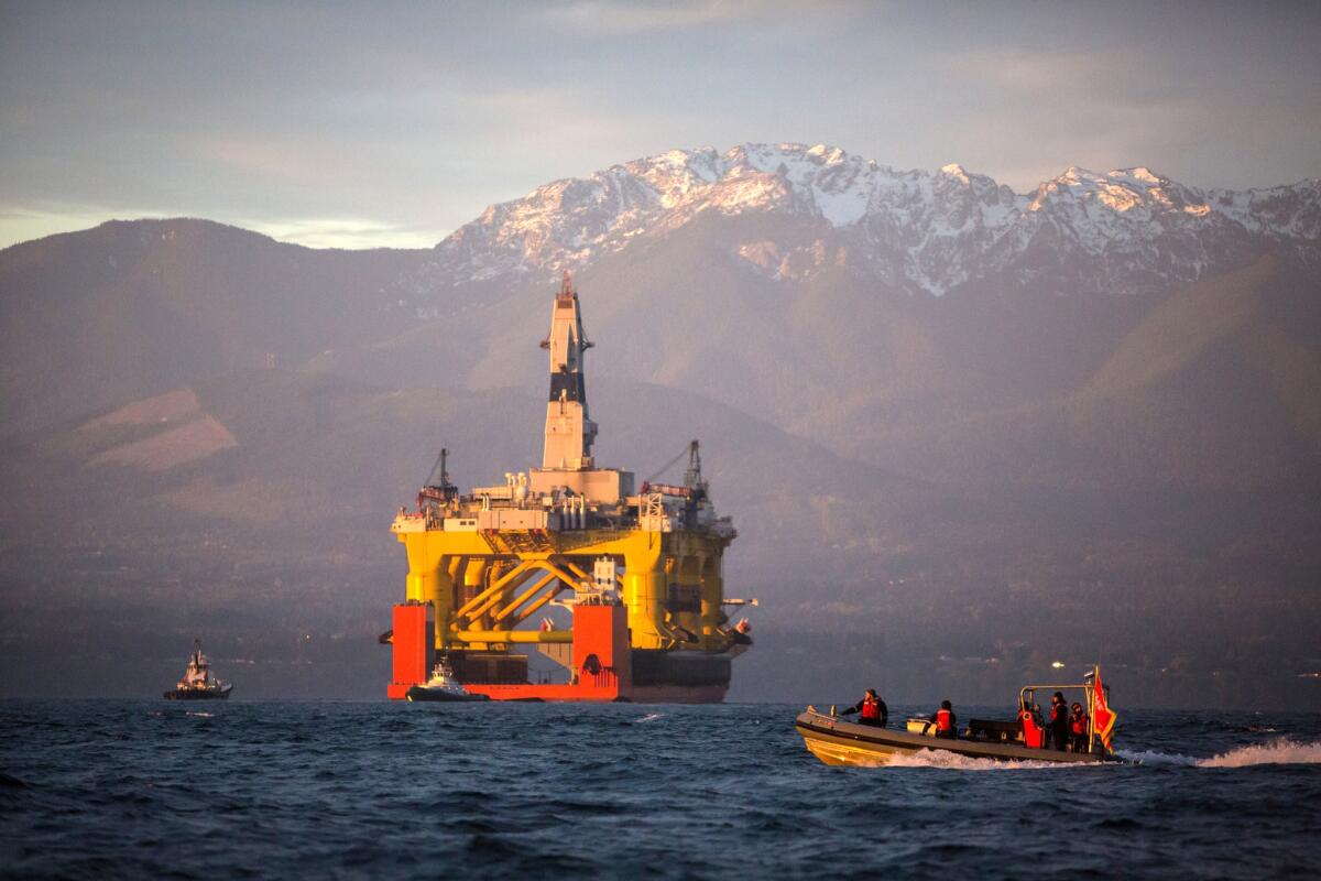 A small boat crosses in front of an oil drilling rig as it arrives in Port Angeles, Wash., aboard a transport ship after traveling across the Pacific on April 17, 2015.