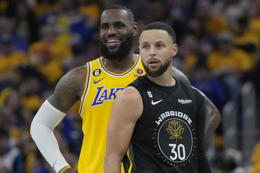 Lakers forward LeBron James stands behind Golden State Warriors guard Stephen Curry