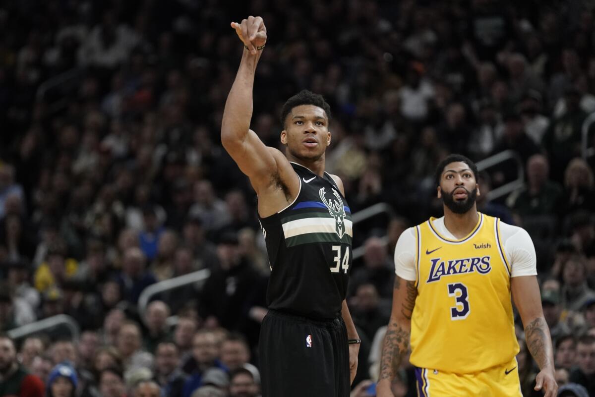 Giannis Antetokounmpo makes a three-pointer in front of Anthony Davis.