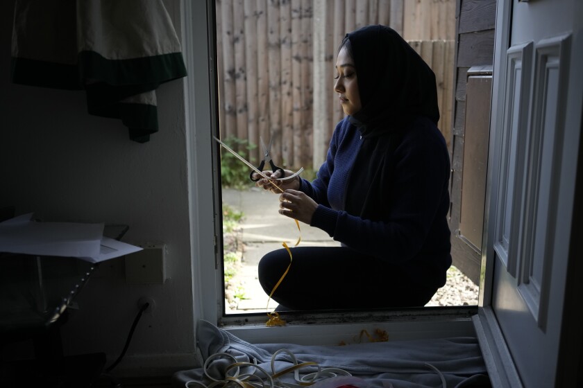 Bilqis Alam, an energy advisor from the South East London Community Energy co-operative (Selce), installs draught proofing rubber strips to the front door frame of the home of her client Tia Rutherford, in south east London, Tuesday, March 22, 2022. People across the United Kingdom will face tough choices in coming months as energy costs for millions of households are set to rise by 54% on Friday. It's the second big jump in energy bills since October, and a third may be ahead as rebounding demand from the COVID-19 pandemic and now Russia's war in Ukraine push energy prices higher. (AP Photo/Matt Dunham)