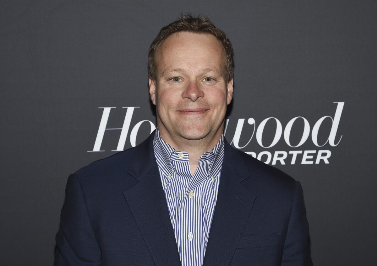 a man in a suit jacket and button-down smiles 