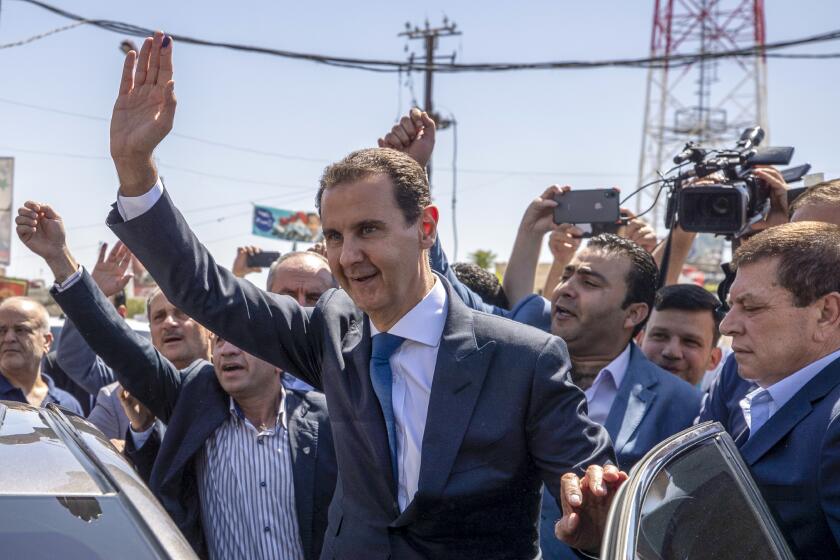 FILE - Syrian President Bashar Assad, center, waves to his supporters at a polling station during the Presidential elections in the town of Douma, in the eastern Ghouta region, near the Syrian capital Damascus, Syria, May 26, 2021. President Bashar Assad will head to China later this week in his first visit to Beijing since the country's conflict started 12 years during which China was one of his main backers, his office said Tuesday. (AP Photo/Hassan Ammar, File)