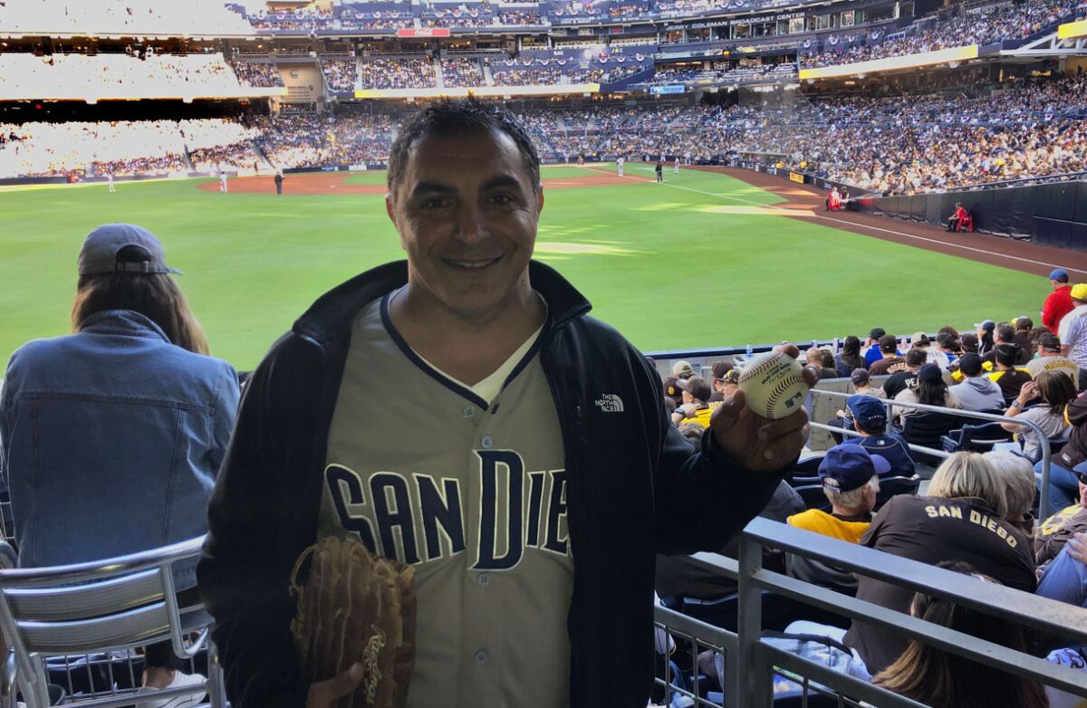 Tim Abbo holds up home run ball hit by Padres' C.J. Abrams that Abbo caught in second inning of game against Atlanta.