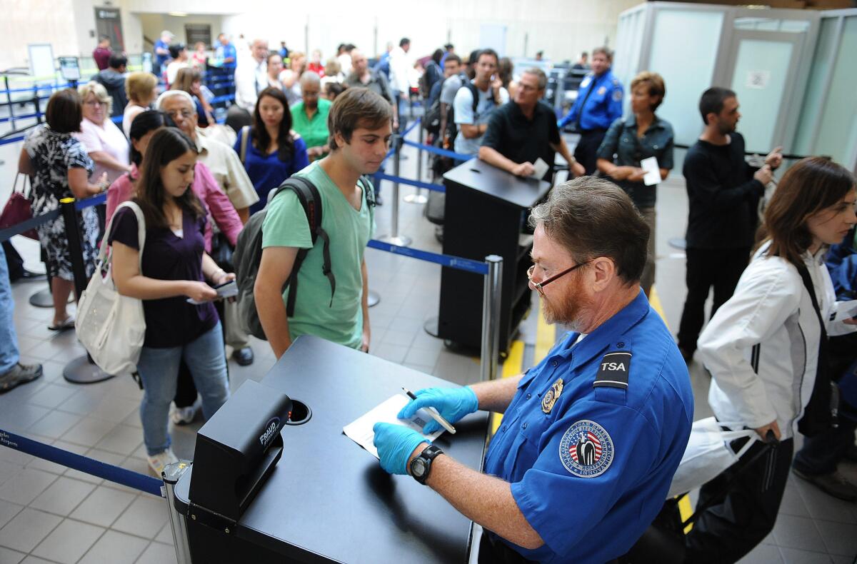 A TSA agent checks the identification of travelers at Los Angeles International Airport. The TSA is offering the public cash for ideas to speed up screening lines.