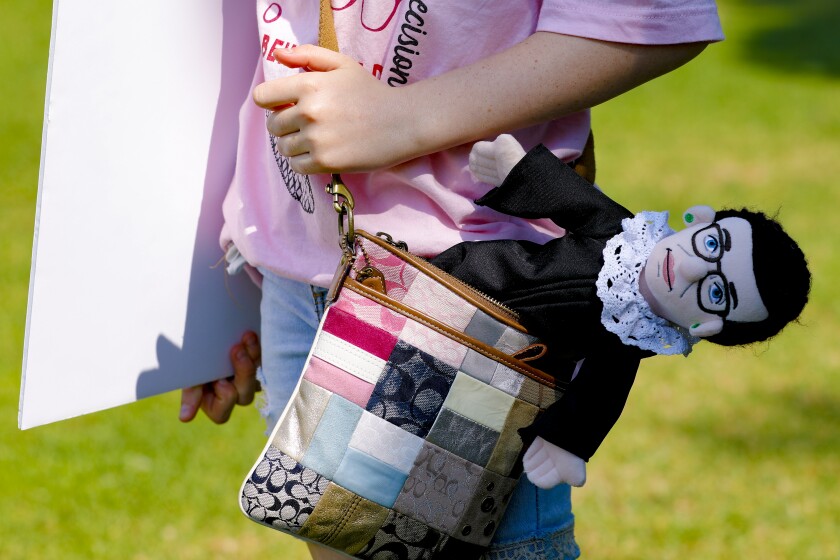 A young girl carries in her purse a doll resembling Justice Ruth Bader Ginsburg at the Women's March