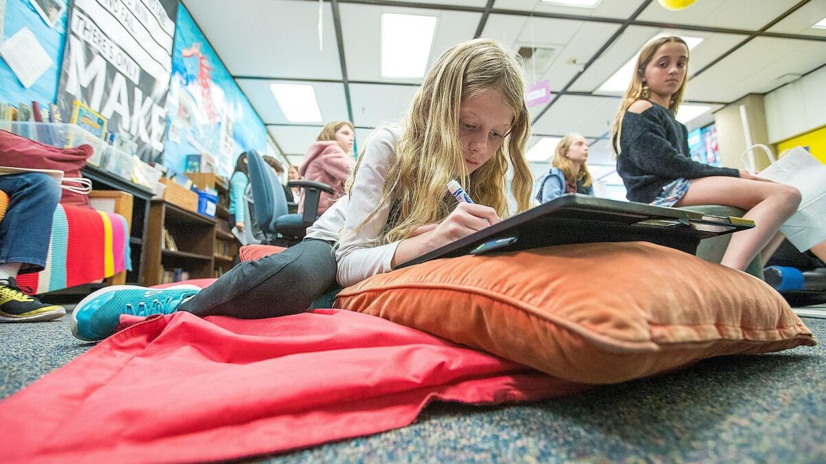 Amanda Garrett, 9, works on a project while lying on a mat on the floor in her fourth-grade class at Andersen Elementary School in Newport Beach.