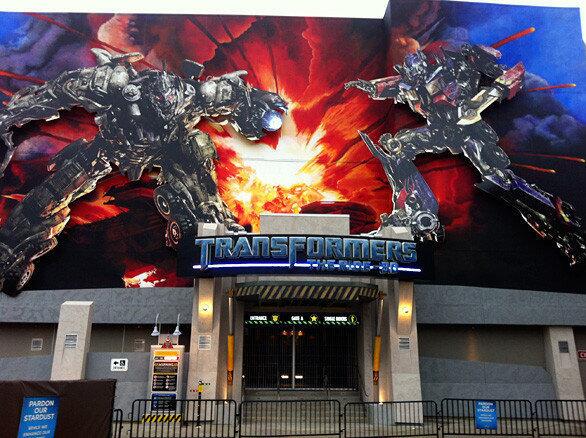 Out front, a towering portrait of Optimus Prime and Megatron in mid-battle hangs over the main entrance of the Transformers ride at Universal Studios Hollywood.
