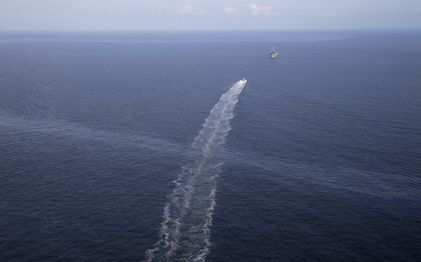 FILE - In this March 31, 2015, file aerial photo, the wake of a supply vessel heading towards a working platform crosses over an oil sheen drifting from the site of the former Taylor Energy oil rig in the Gulf of Mexico, off the coast of Louisiana. A federal appeals court says the owner of Gulf of Mexico oil wells broken in 2004 cannot demand damages from a federal contractor who says his equipment has captured enough oil to fill scores of tank trucks. The 5th U.S. Circuit Court of Appeals on Thursday, July 1, 2021, upheld a district court ruling that Taylor Energy Co. LLC cannot sue Couvillion Group LLC for trespass. (AP Photo/Gerald Herbert, File)