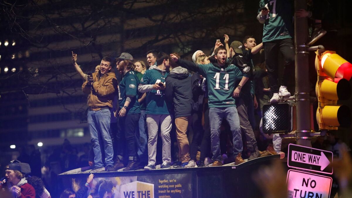 Eagles fans crowd on to the top of a bus shelter.