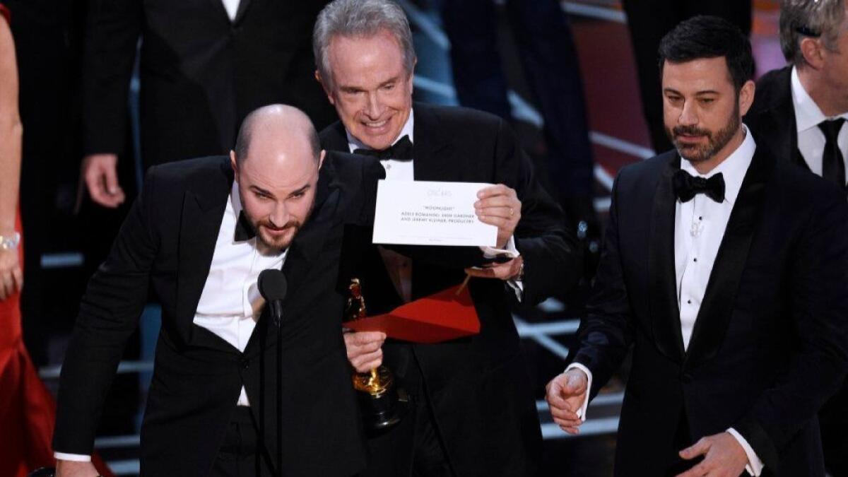 Jordan Horowitz, producer of "La La Land," left, shows the card revealing "Moonlight" as the true winner of best picture at the 2017 Oscars as presenter Warren Beatty and host Jimmy Kimmel, right, look on.