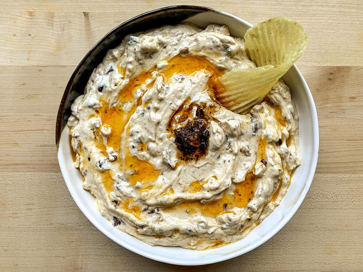 Fried Onion-Chili Crisp Dip in a round bowl surrounded by ruffled potato chips.