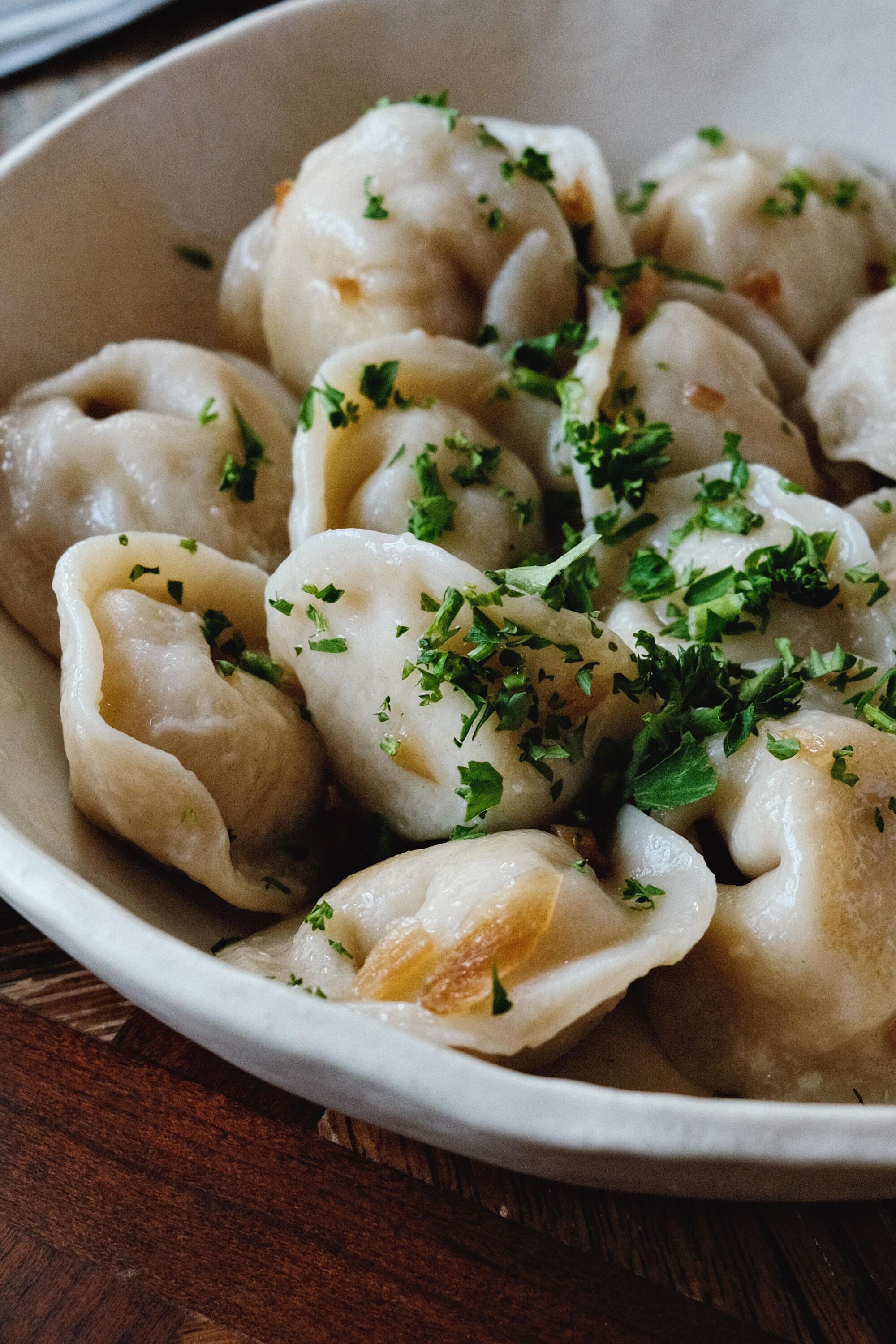 A vertical closeup of parsley-topped pelmeni dumplings at Ukrainian restaurant Mom, Please.