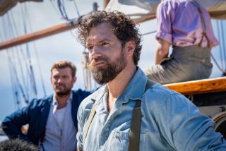 Two beared men standing in the sun on a ship's deck.