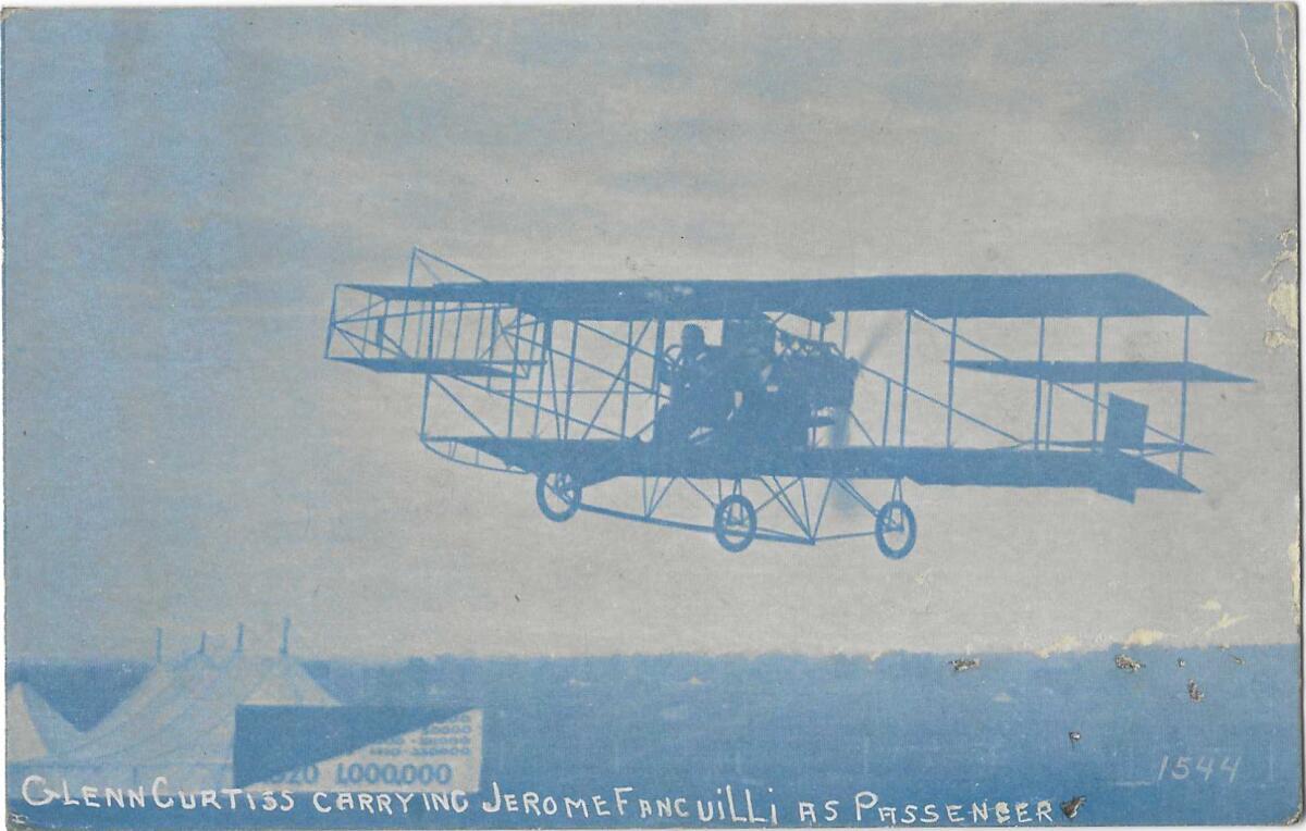 An airplane on a blue-hued postcard. Text: "Glenn Curtiss carrying Jerome Fancuilli as passenger."
