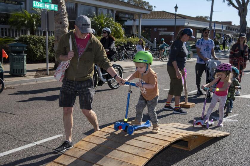 Brian Orr helps kids Atticus and Atlas over a ramp at 2023's Cyclovia.