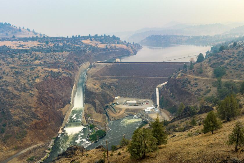 Klamath, CA - August 18: A spillway, left, is filled with water at Iron Gate Dam where modifications to an existing tunnel are underway on Friday, Aug. 18, 2023 in Klamath, CA. The tunnel will be used to drain the lake nearly next year. (Brian van der Brug / Los Angeles Times)