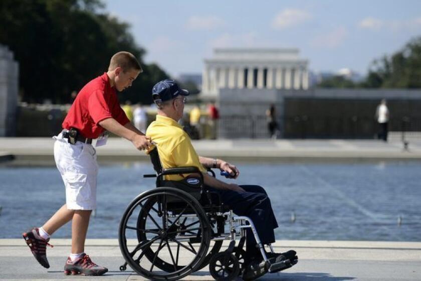 Zach Twedt pushes Robert Olson, a Korean War veteran, on a tour of the World War II Memorial in Washington.