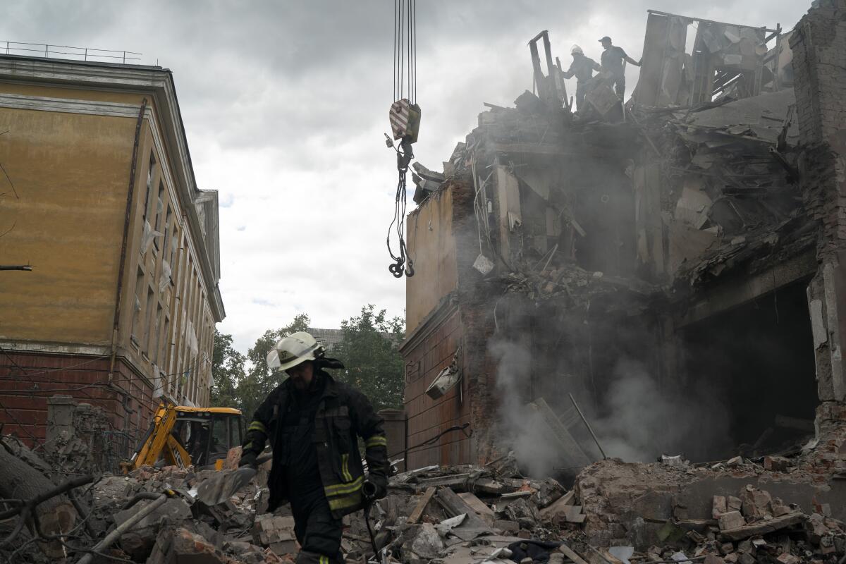 Firefighters amid debris of building damaged by shelling in Ukraine