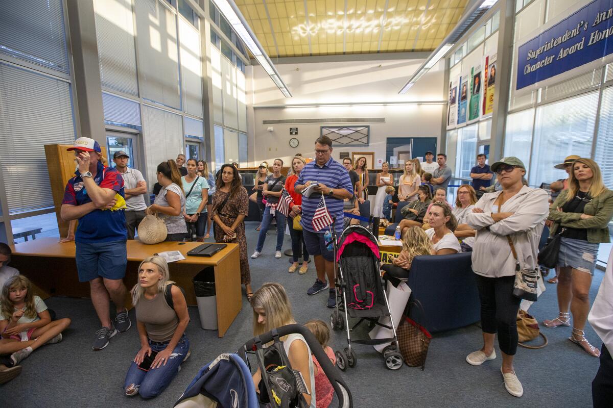 Parents and children wait in the lobby outside of Newport-Mesa Unified School District board room during a meeting Tuesday.