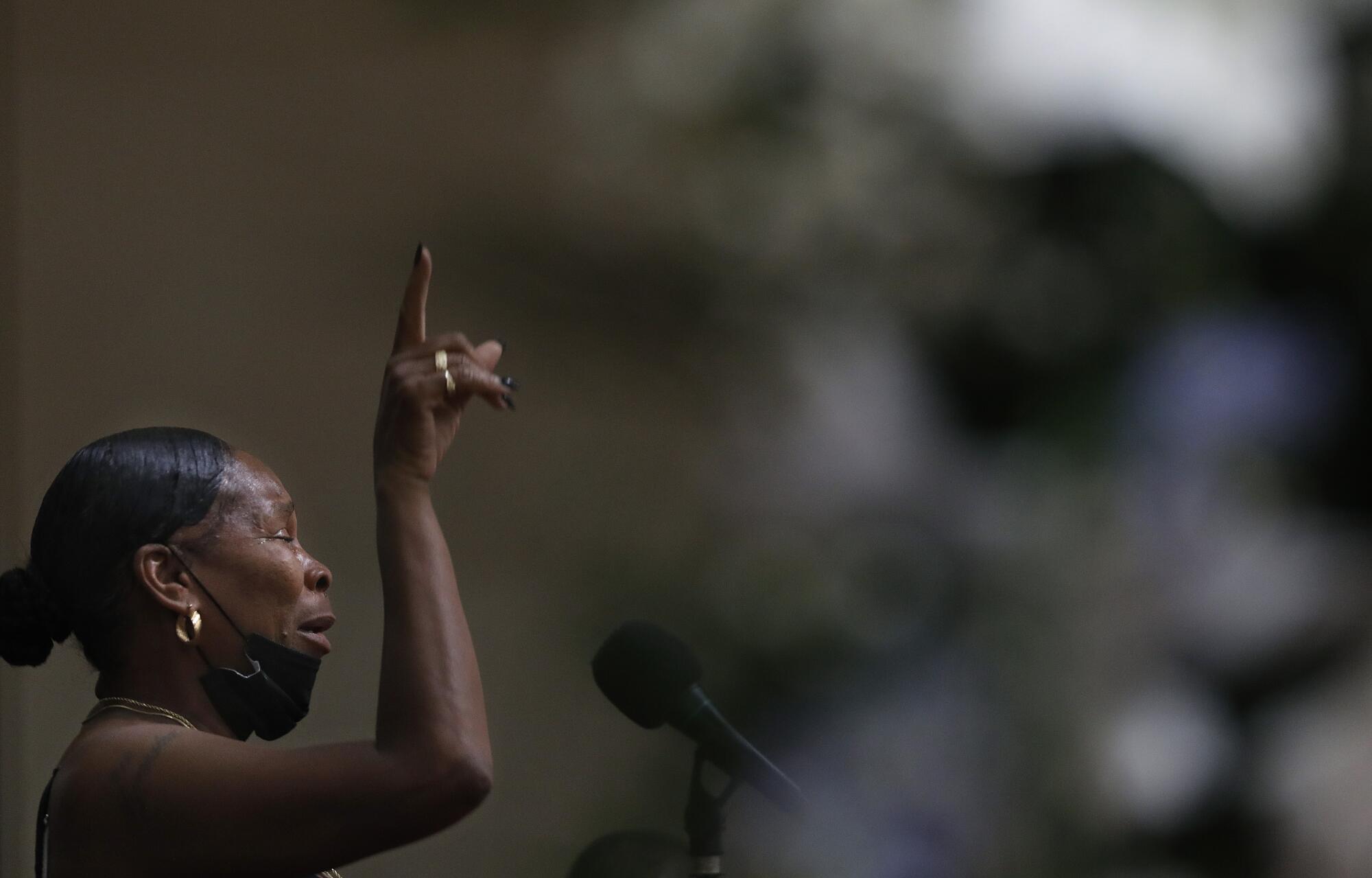 A woman cries while speaking into a microphone 