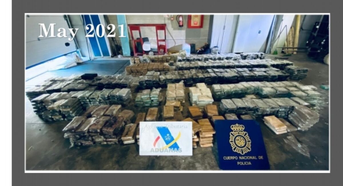 Bags of cocaine are stacked and arranged in rows on a concrete floor.