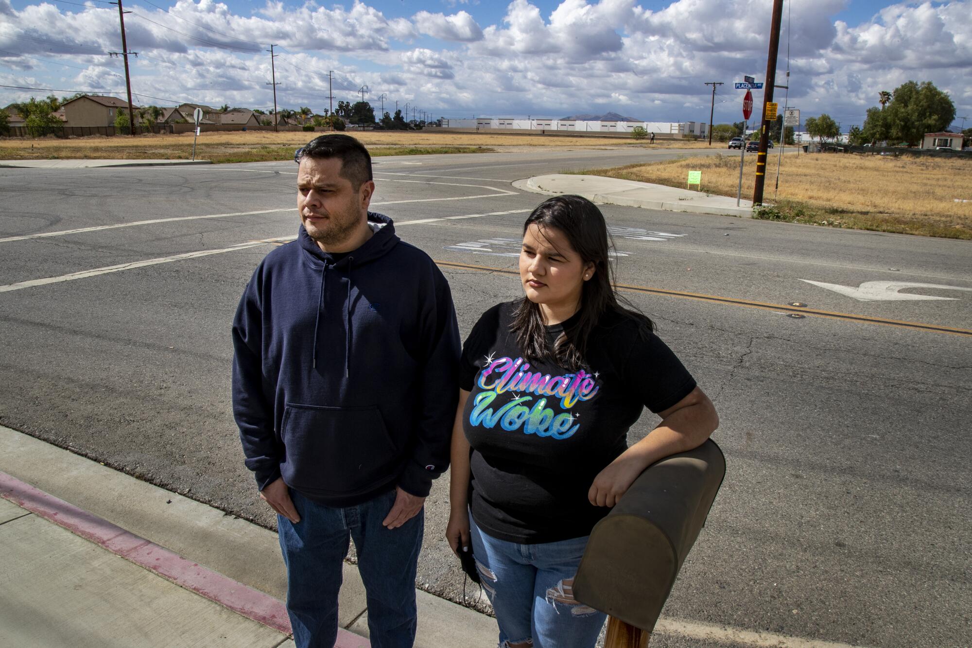 Rebecca Hernandez, 18 and her dad Mike Hernandez stand near their home with a giant warehouse in the background