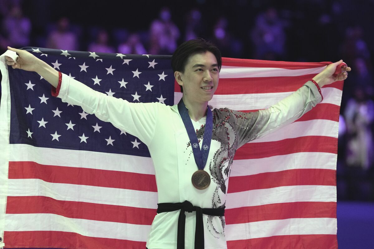 Vincent Zhou celebrates his bronze medal by holding up the American flag.
