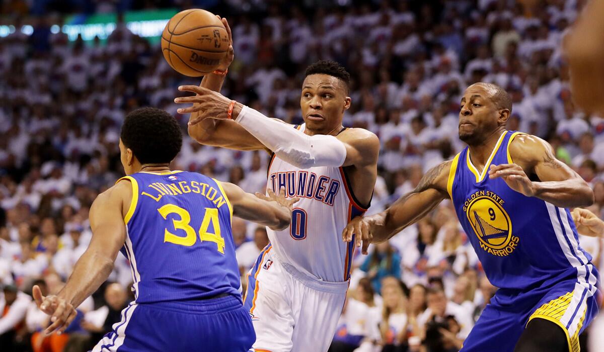 Oklahoma City Thunder's Russell Westbrook, center, passes against Golden State Warriors' Shaun Livingston, left, and Andre Iguodala in the third quarter of Game 4 of the NBA Western Conference Finals on Tuesday.